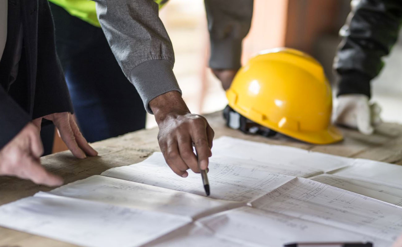 Construction workers with site plan and hard hats